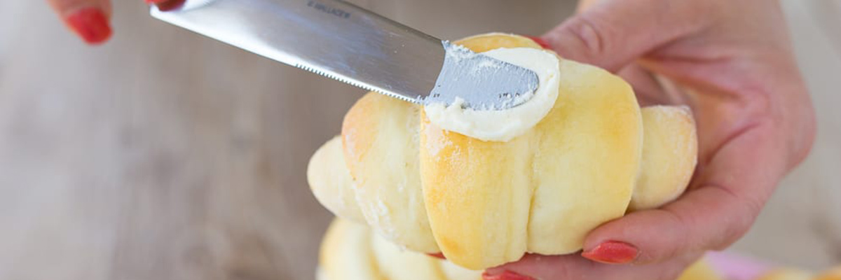 Knife buttering a roll