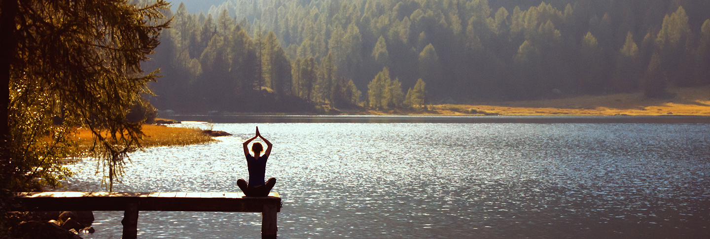 Woman sitting on dock by mountain lake